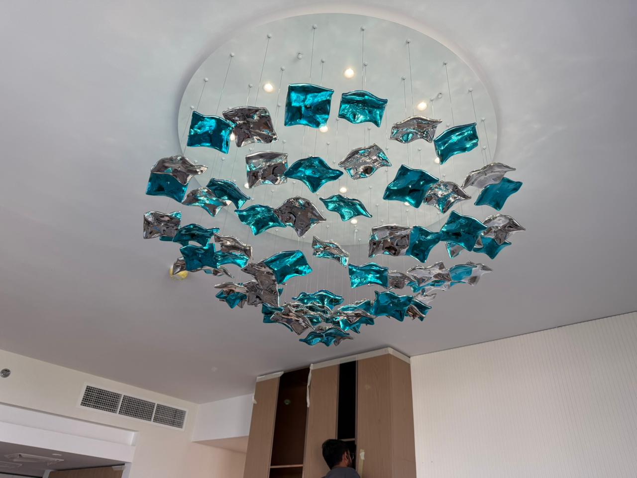 Close-up of teal and silver sculptural chandelier installation details in UAE