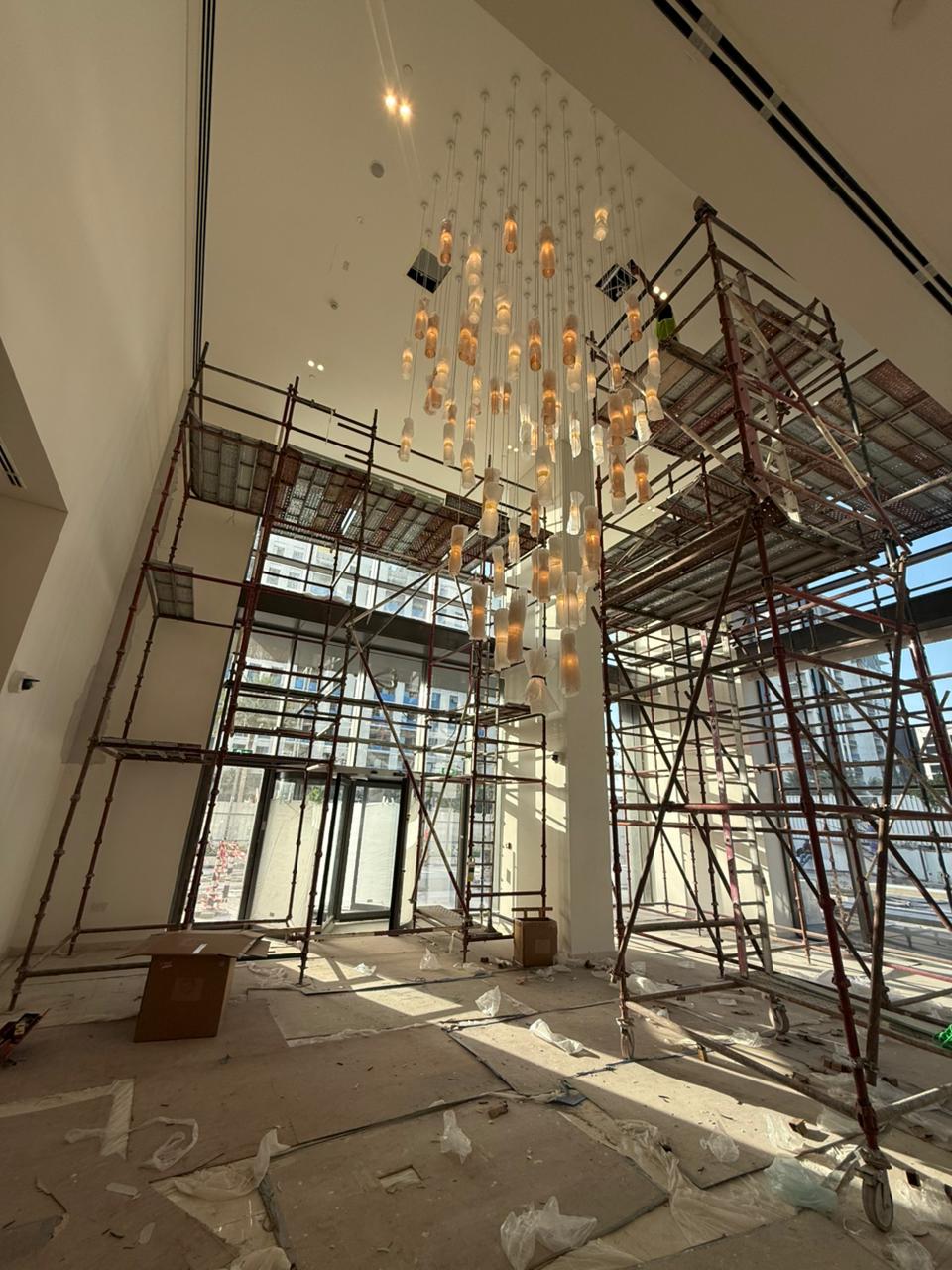 Professional chandelier installation team working on large-scale fixture in Dubai building