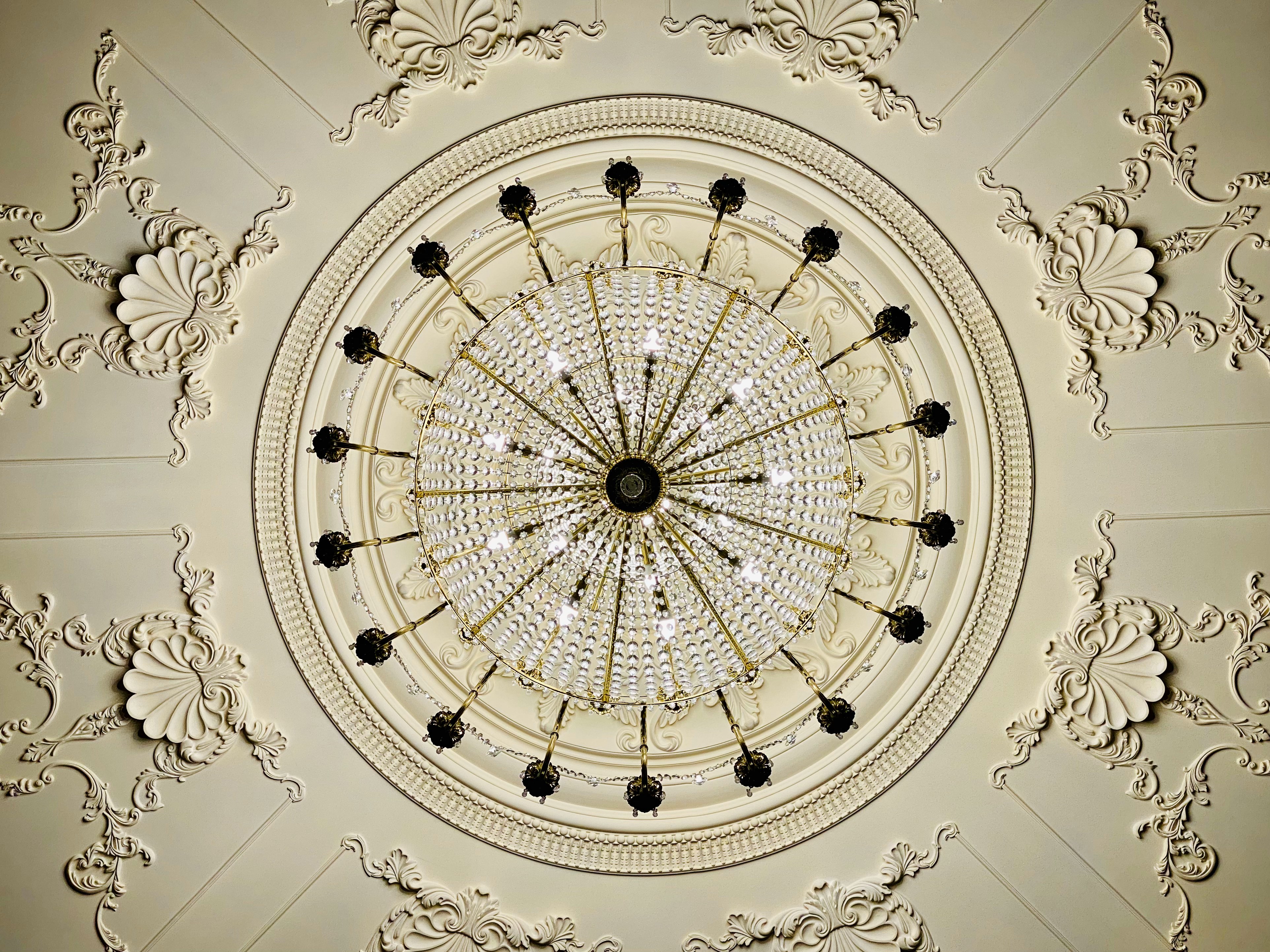 Top-down view of circular crystal chandelier with ornate ceiling integration