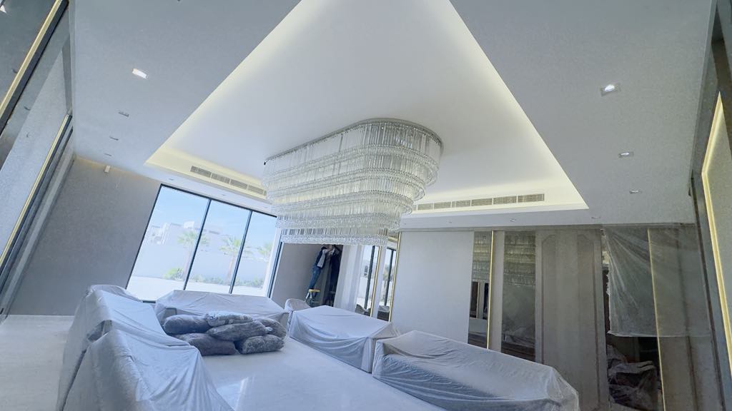 Large curved tiered crystal chandelier installed in spacious UAE hall