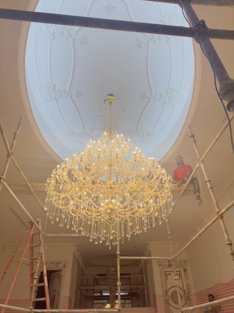 Grand ornate crystal chandelier being installed by professional team