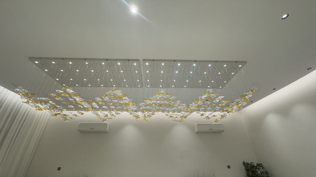 Rectangular chandelier with golden and clear glass leaves installed in Dubai