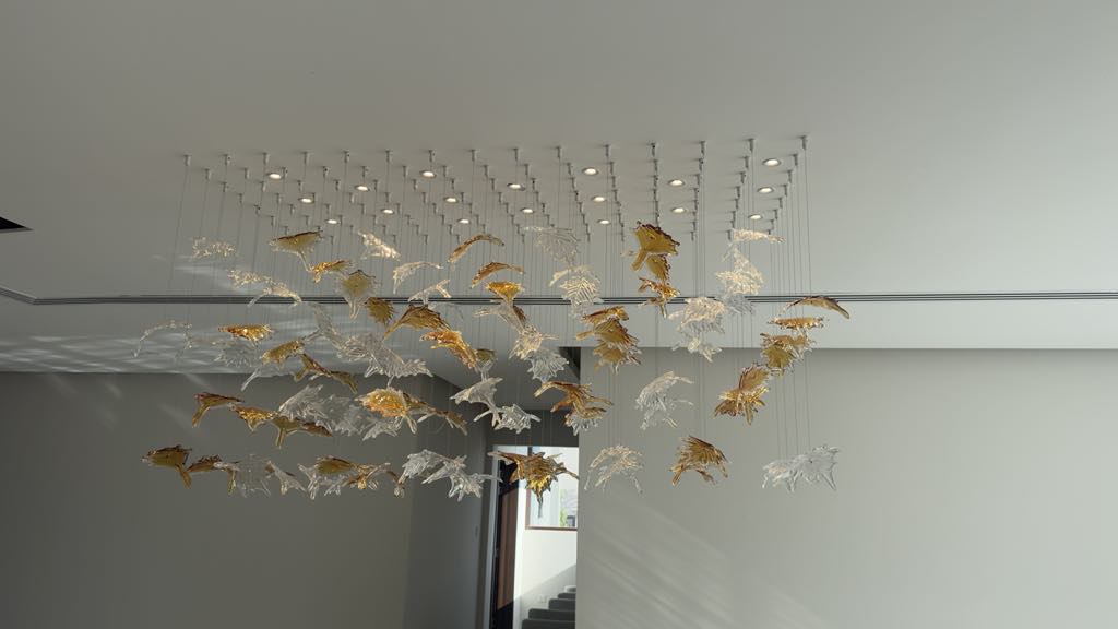 Wide chandelier with golden and clear glass leaves in large UAE space